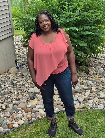 Picture of a person standing on a lawn in front of rocks.
