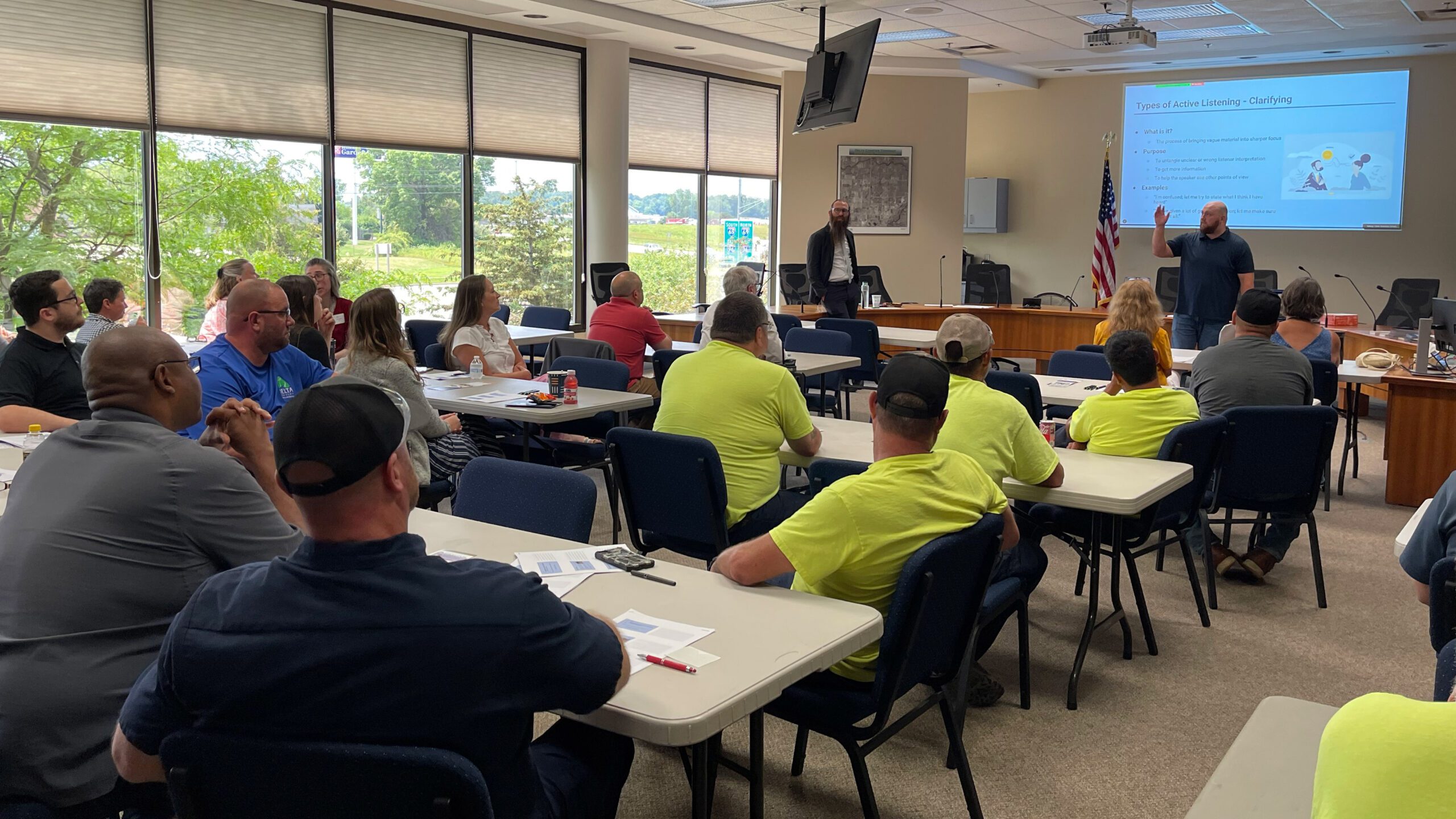 people sitting at desks in a training room listening to trainers